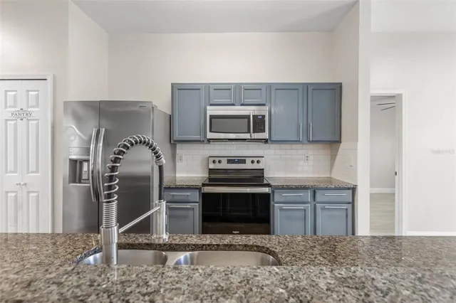 a kitchen with stainless steel appliances granite countertop a stove a refrigerator and a sink