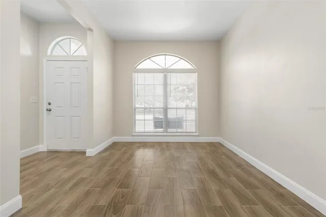 an empty room with wooden floor windows and exposed bricks