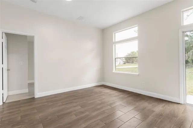 an empty room with wooden floor and windows