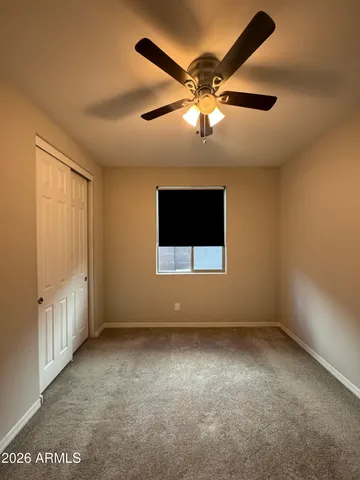 an empty room with a ceiling fan and a window