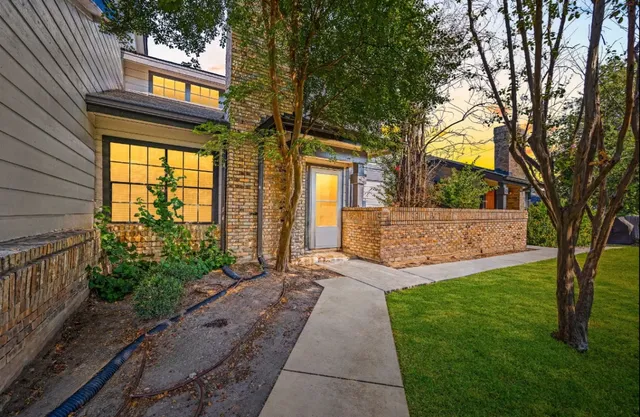 a view of a house with a small yard and a large tree