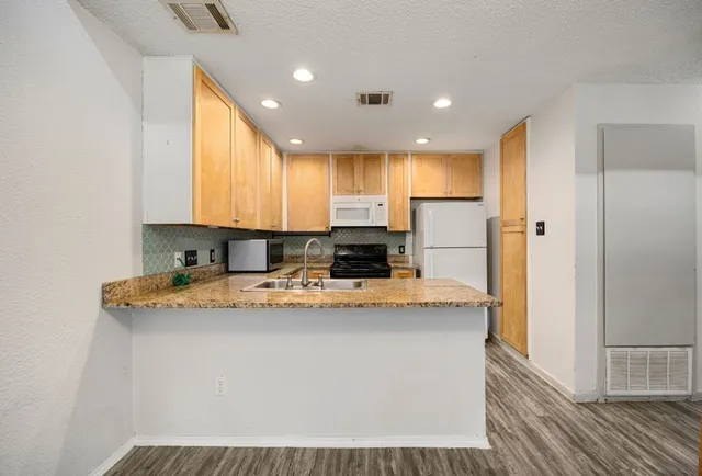 a kitchen with stainless steel appliances granite countertop a sink a refrigerator and a stove