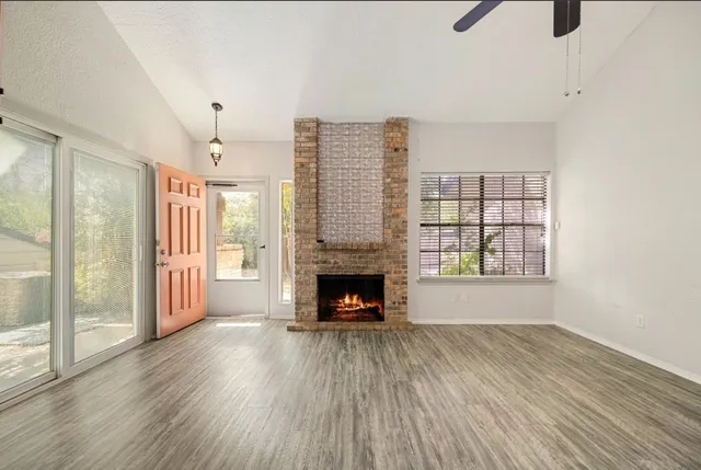 a view of an empty room with wooden floor fireplace and a window