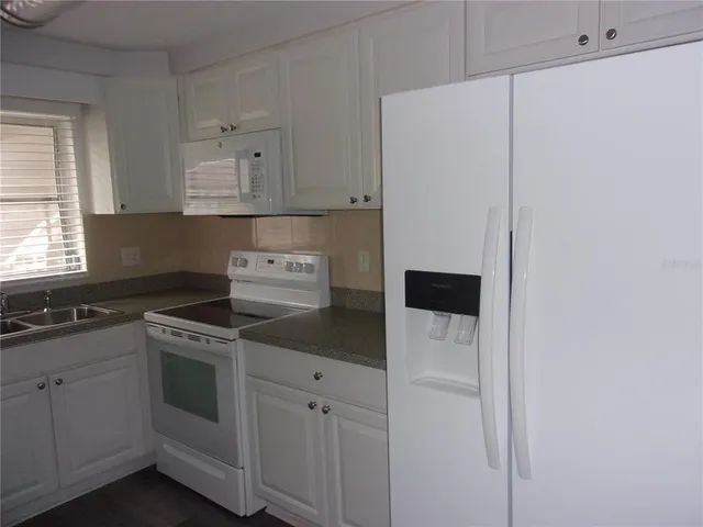 a kitchen with white cabinets and white appliances