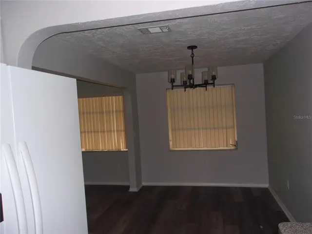 a hallway with a chandelier fan and wooden floor