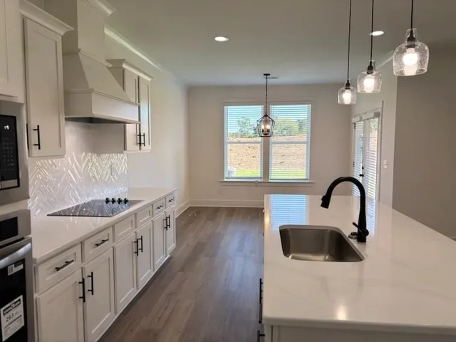 a kitchen with kitchen island stainless steel appliances a stove a sink a oven a dining table and chairs with wooden floor