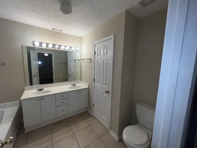 a spacious bathroom with a double vanity sink toilet and shower