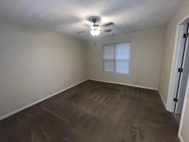 an empty room with a chandelier fan and windows