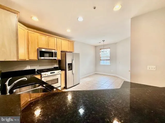 a kitchen with stainless steel appliances granite countertop a stove a sink dishwasher and a refrigerator with wooden floor