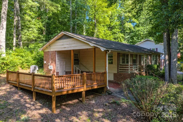 a view of a house with a wooden deck and a forest