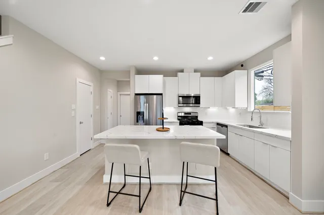 a kitchen with kitchen island a stove a table and chairs in it