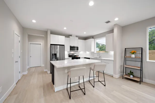 a kitchen with stainless steel appliances a microwave a stove a refrigerator and a refrigerator with wooden floor