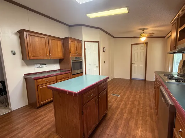 a kitchen with kitchen island granite countertop wooden cabinets a sink and a stove
