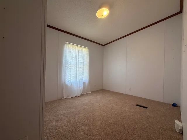 an empty room with a chandelier fan and windows