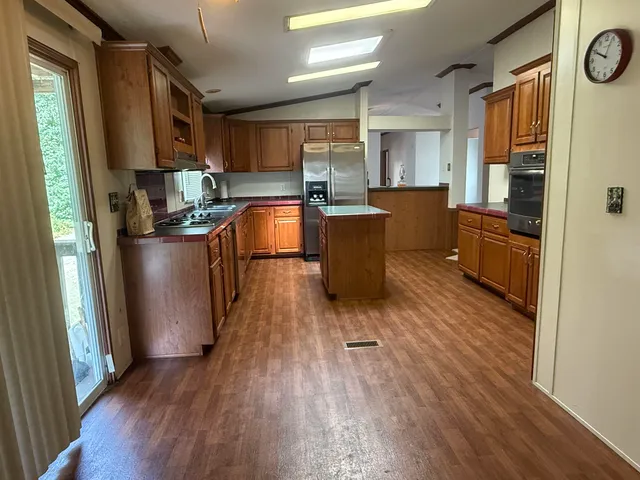 a kitchen with stainless steel appliances a refrigerator a sink dishwasher a stove and white countertops with wooden floor