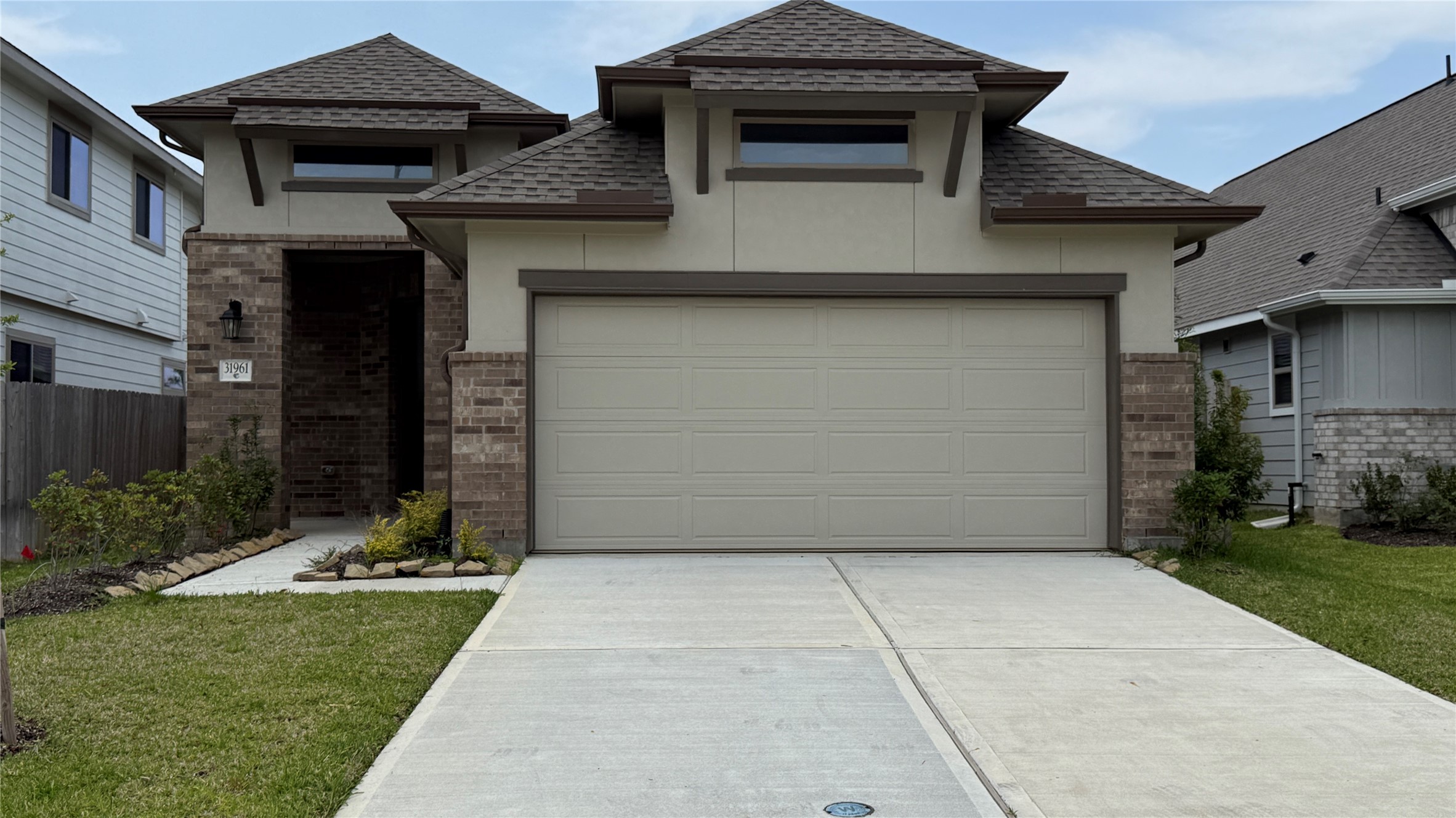 31961 Retama Rnch Drive Spring, TX 77386 - Photo 2 of 25 This is a modern, single-story home featuring a two-car garage and a clean, landscaped front yard. The exterior combines brick and stucco finishes with a welcoming entryway.