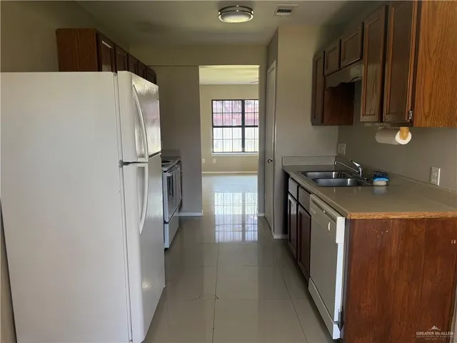 a kitchen with a refrigerator a stove top oven and cabinets
