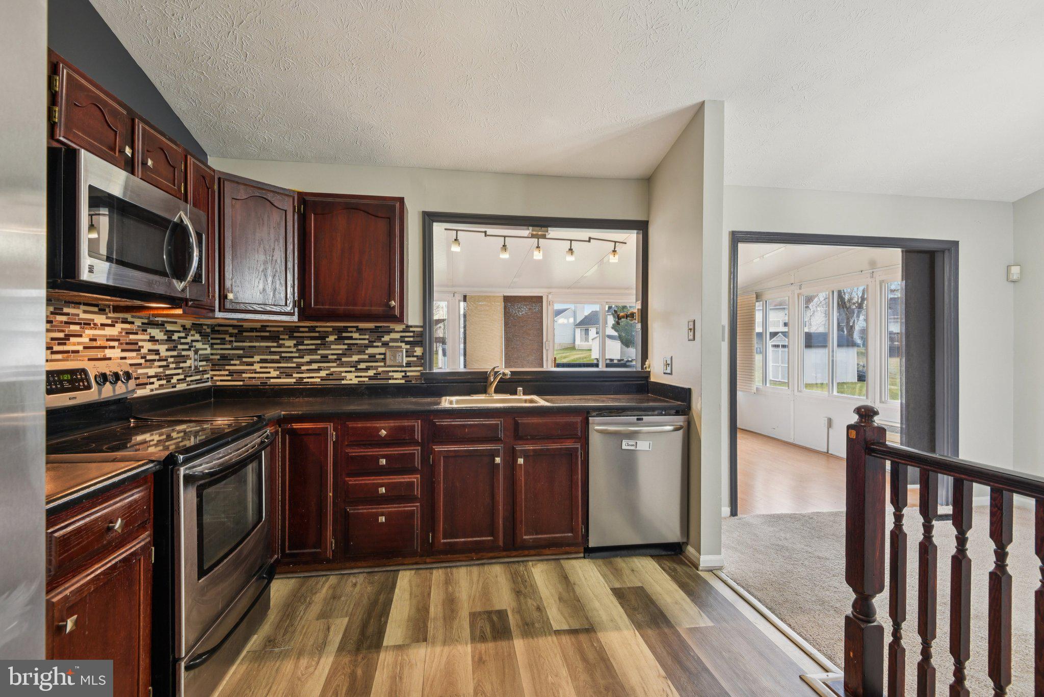 7934 Galloping Circle Windsor Mill, MD 21244 - Photo 11 of 38 a kitchen with stainless steel appliances granite countertop wooden cabinets a stove top oven a sink and dishwasher