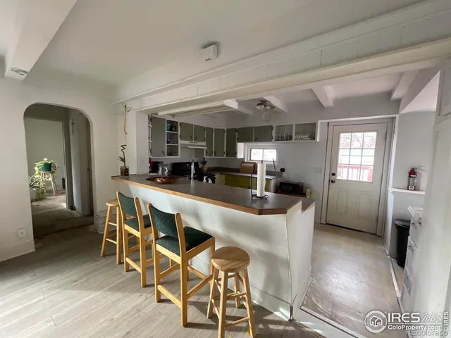 a dining hall with stainless steel appliances kitchen island granite countertop a table chairs and a refrigerator