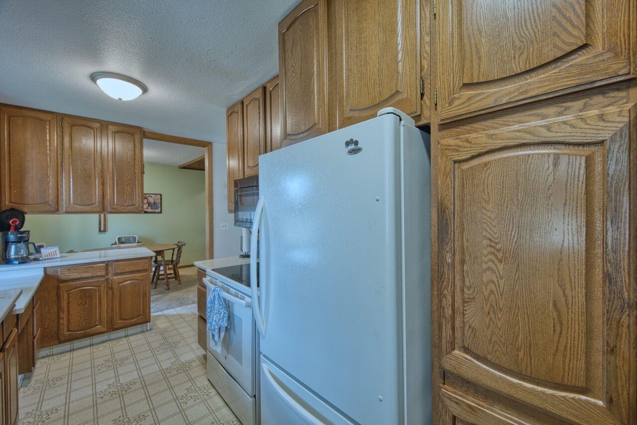 312 South 2nd Street West Aurora, MN 55705 - Photo 10 of 41 Kitchen with wood finish cabinets, white appliances, light floors, light countertops, and a textured ceiling
