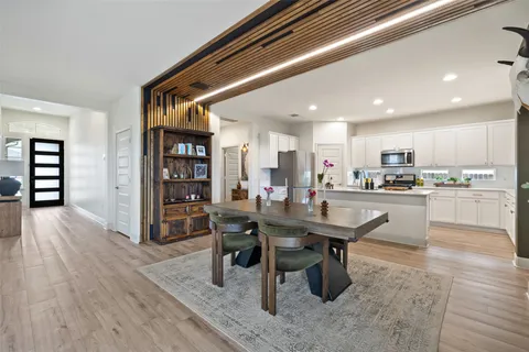 a dining hall with stainless steel appliances kitchen island granite countertop a table chairs and a refrigerator