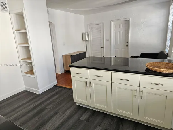 a bath room with granite countertop cabinets and a wooden floor