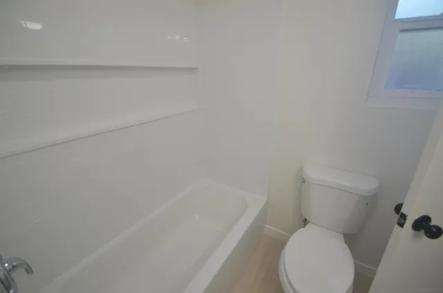 a white toilet sitting next to a bath tub