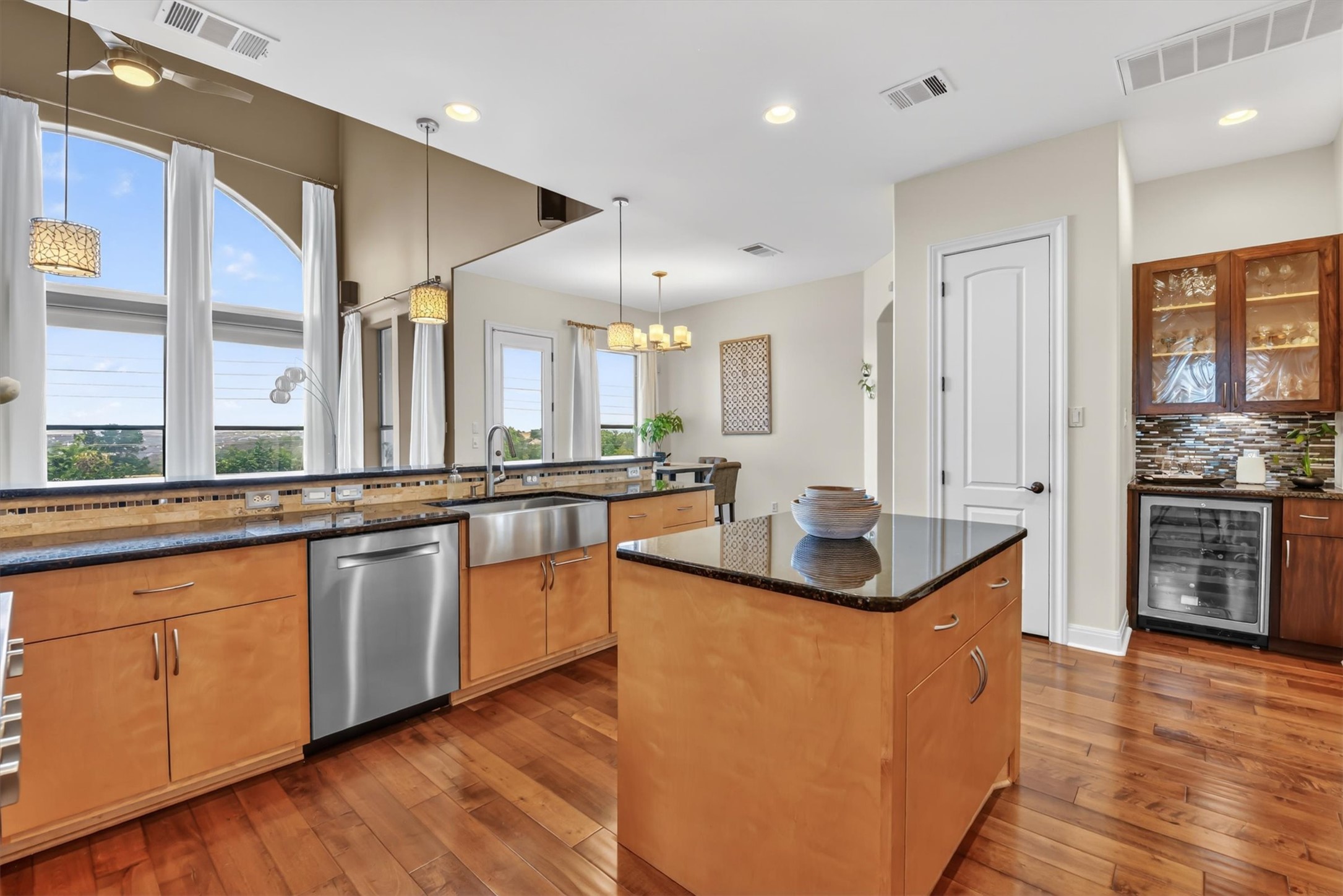 2000 Rio Mesa Drive Austin, TX 78732 - Photo 18 of 39 Kitchen featuring hardwood floors, light-toned cabinetry, stainless steel appliances, and a large arched window with white curtains
