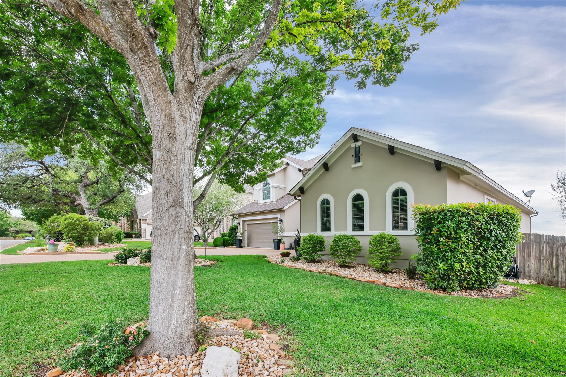 2000 Rio Mesa Drive Austin, TX 78732 - Photo 2 of 39 The property features a well-maintained lawn, mature trees, and a stucco exterior with arched windows