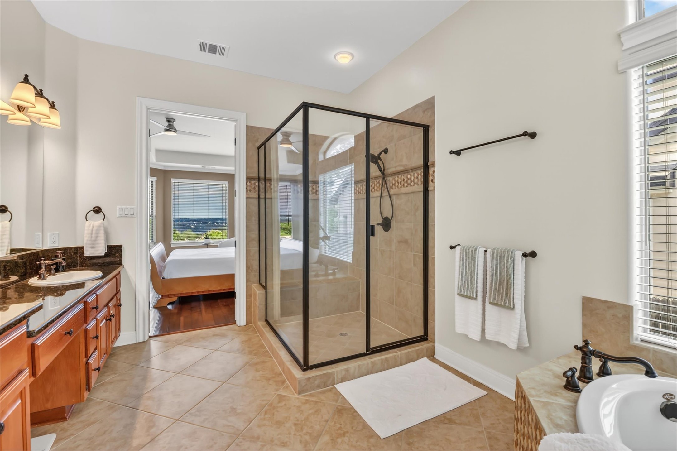 2000 Rio Mesa Drive Austin, TX 78732 - Photo 23 of 39 The bathroom features a tiled floor, a glass-enclosed shower with tiled walls, and a vanity with dual sinks and a dark countertop