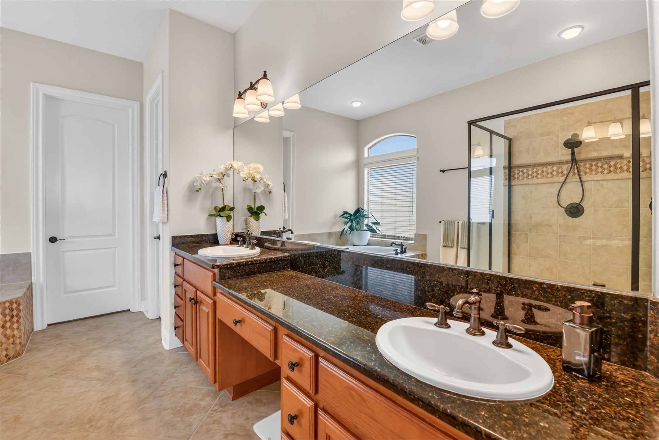 2000 Rio Mesa Drive Austin, TX 78732 - Photo 24 of 39 The bathroom features a double vanity with granite countertops and rich wood cabinetry, alongside a tiled shower with a glass enclosure