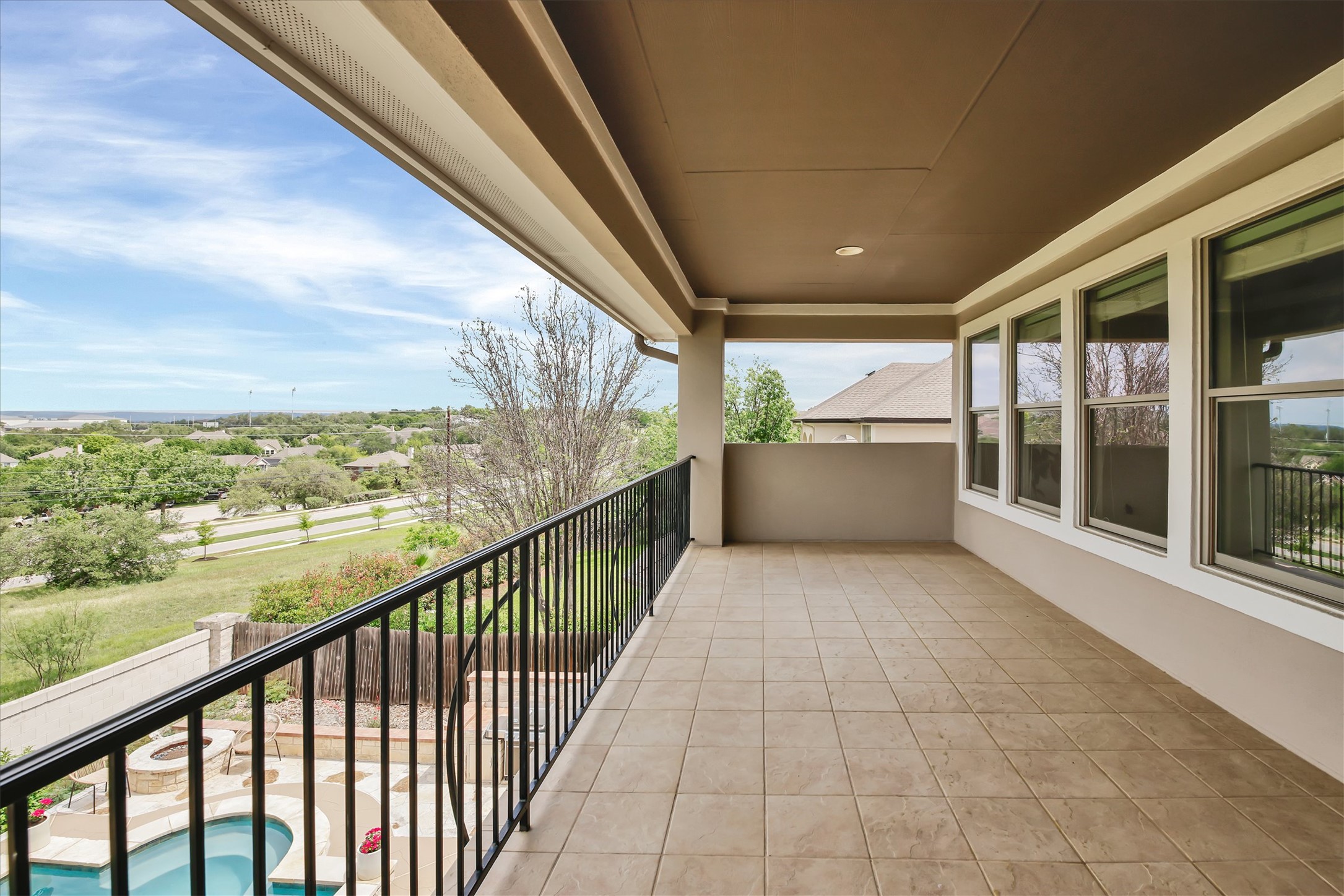 2000 Rio Mesa Drive Austin, TX 78732 - Photo 29 of 39 The property features a spacious covered balcony with tiled flooring and a sturdy black railing, offering views of the surrounding landscape and a swimming pool