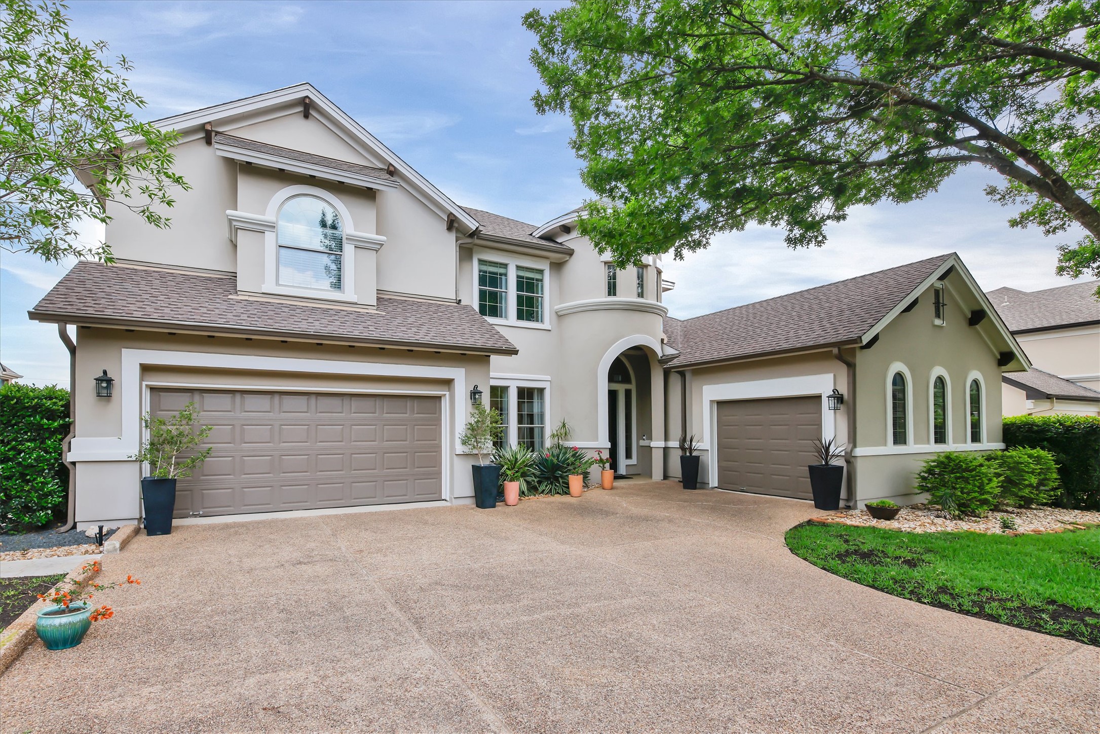 2000 Rio Mesa Drive Austin, TX 78732 - Photo 3 of 39 The property features a stucco exterior with multiple gables and dormer windows, a large driveway, and an attached garage