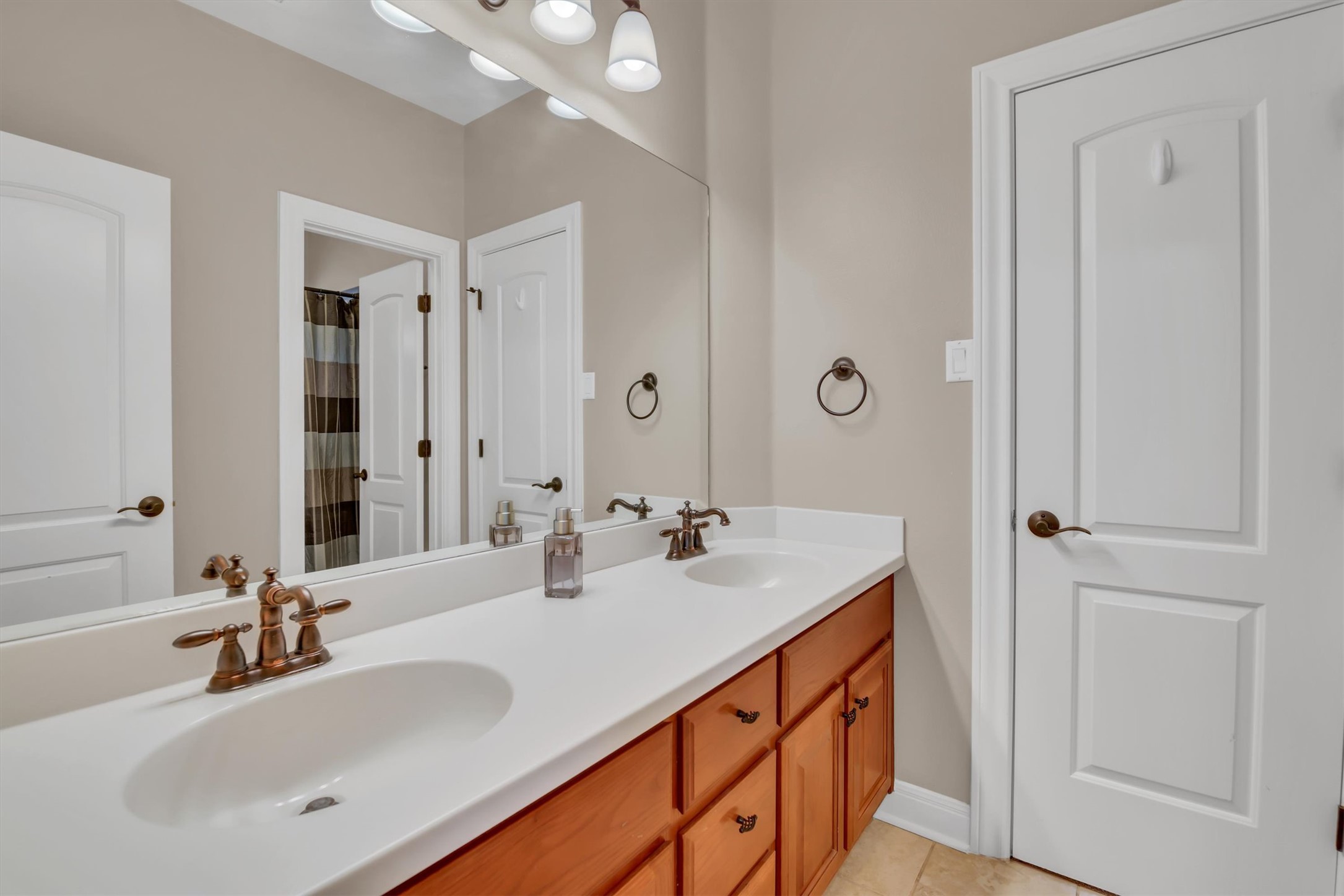 2000 Rio Mesa Drive Austin, TX 78732 - Photo 31 of 39 The property features a vanity with two integrated sinks, a light-colored countertop, and a wood-toned cabinet with bronze hardware