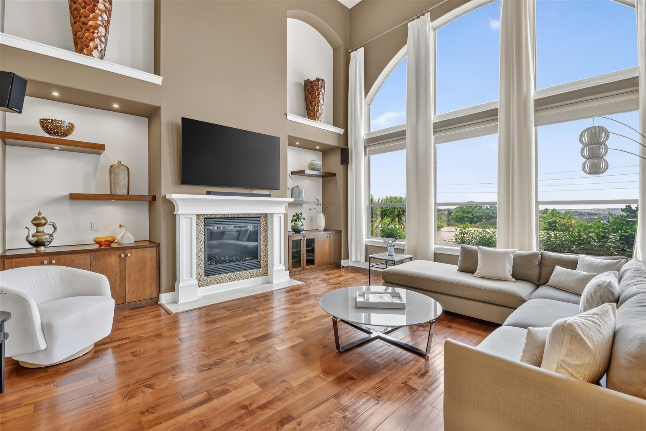 2000 Rio Mesa Drive Austin, TX 78732 - Photo 6 of 39 Spacious living area featuring hardwood floors, a white mantel fireplace, and expansive windows providing abundant natural light and exterior views