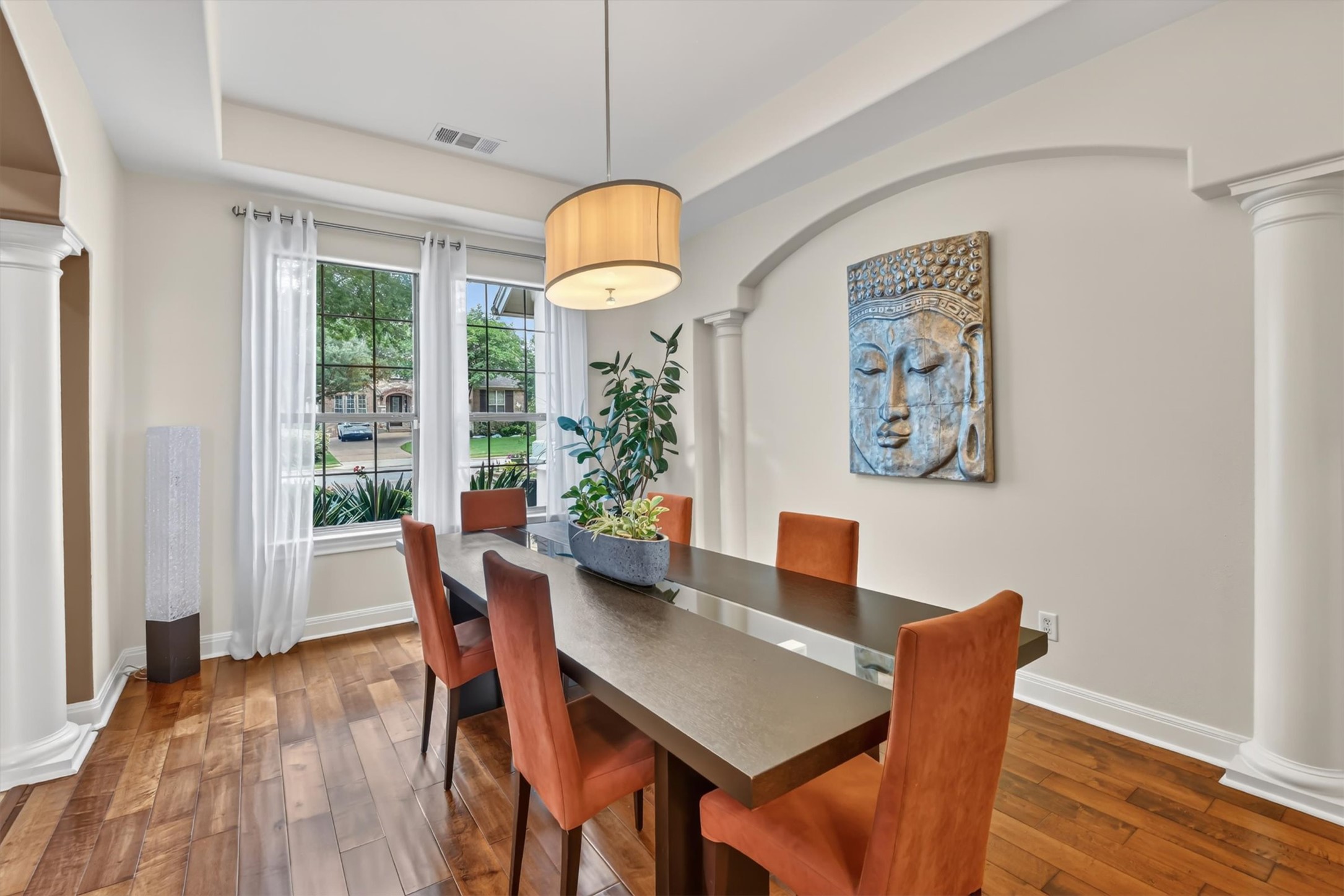 2000 Rio Mesa Drive Austin, TX 78732 - Photo 9 of 39 Dining area featuring hardwood floors, a large window, decorative columns, and an archway