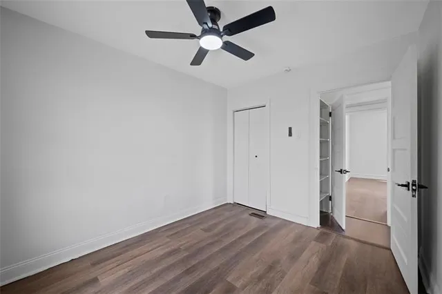 an empty room with wooden floor fan and windows