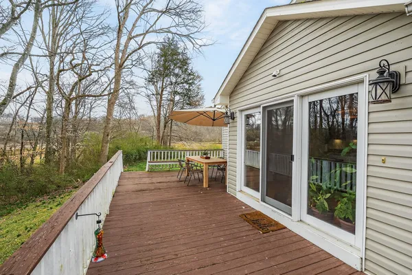 a view of a patio with couches and table and chairs with wooden floor and fence