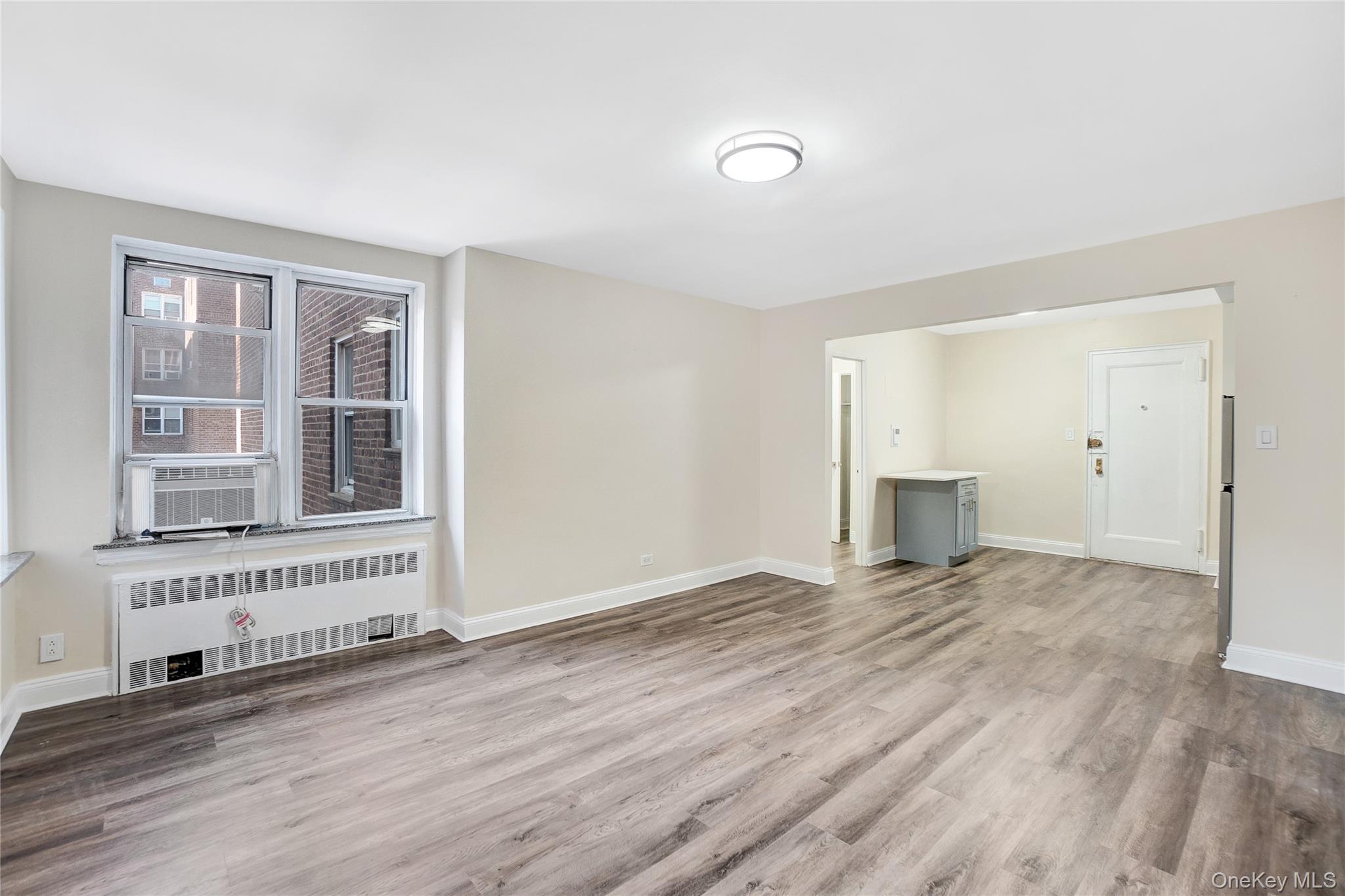 105-24 64th Road, Unit 4L Queens, NY 11375 - Photo 4 of 14 an empty room with wooden floor and windows