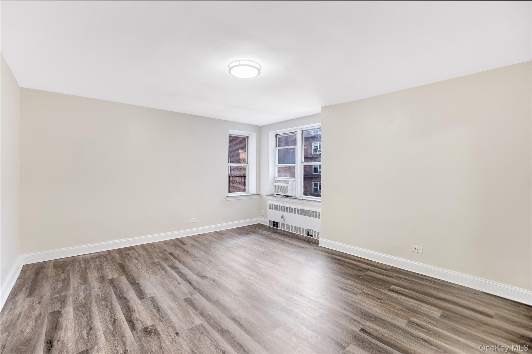 105-24 64th Road, Unit 4L Queens, NY 11375 - Photo 5 of 14 an empty room with wooden floor and windows
