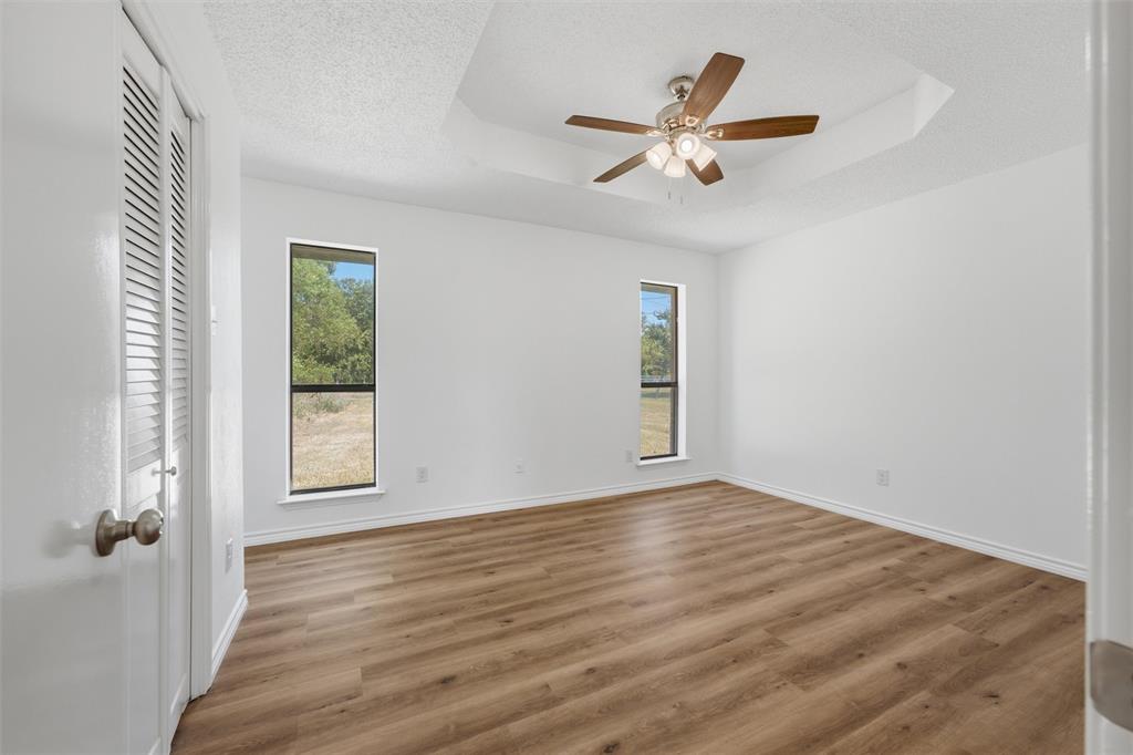 124 Prairie Creek Road Red Oak, TX 75154 - Photo 12 of 17 Spacious interior bedroom featuring wood-finish flooring throughout, multiple windows with natural light exposure, ceiling fan with integrated lighting, and clean white walls with fresh finishes