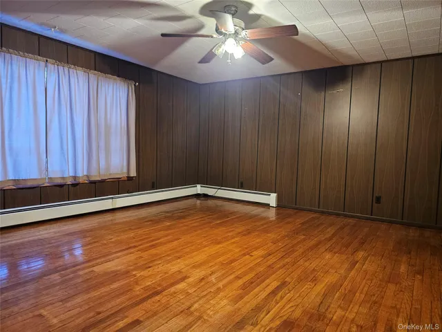 an empty room with wooden floor and fan