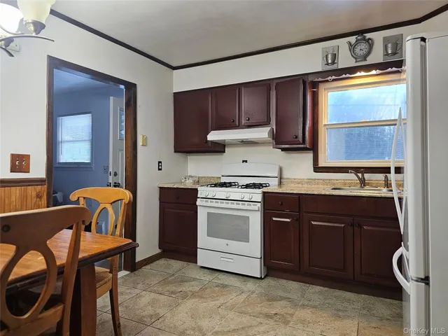 a kitchen with stainless steel appliances granite countertop a stove top oven a sink and a dining table with granite countertops