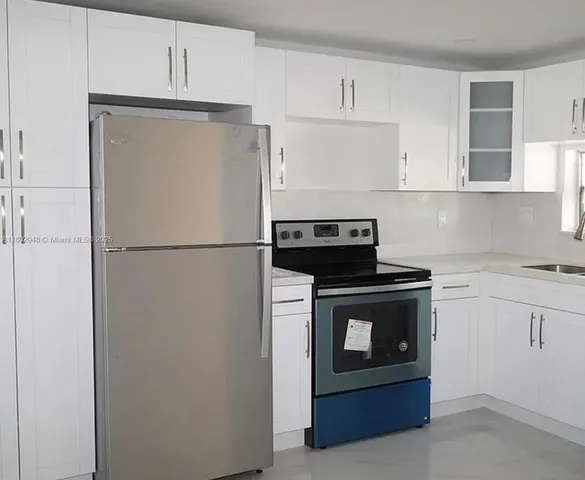 a kitchen with a refrigerator stove and white cabinets