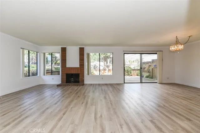 an empty room with wooden floor fireplace and windows