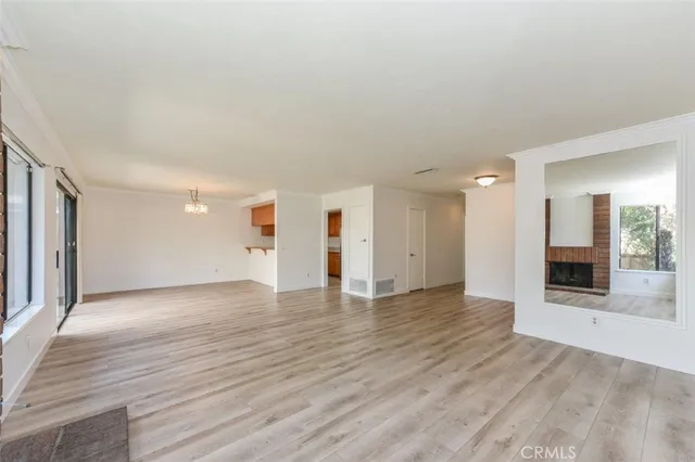 a view of a livingroom with wooden floor and kitchen space
