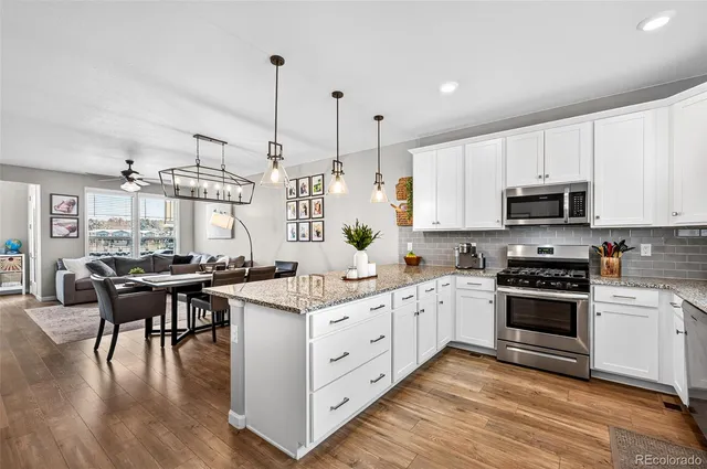 a kitchen with appliances a sink a stove a dining table and chairs