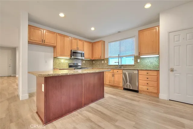 a kitchen with stainless steel appliances granite countertop a refrigerator a sink dishwasher and a stove with wooden floor