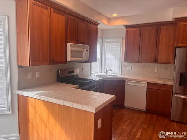 a kitchen with granite countertop wooden cabinets a sink and a stove with wooden floor