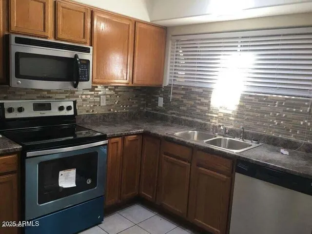 a kitchen with granite countertop a sink stove and microwave
